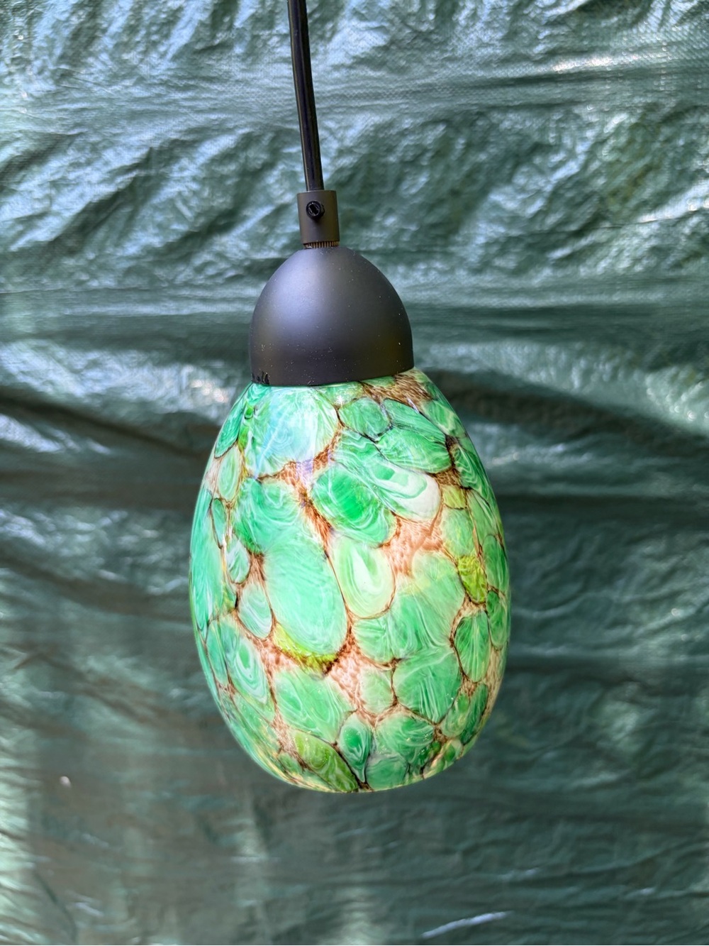 light fixture features a green art glass shade with brown veining